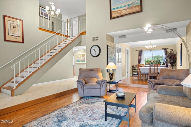 living room with visible vents, crown molding, stairway, wood finished floors, and a notable chandelier
