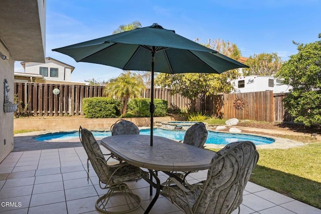 view of patio / terrace with outdoor dining space, an in ground hot tub, a fenced backyard, and a fenced in pool