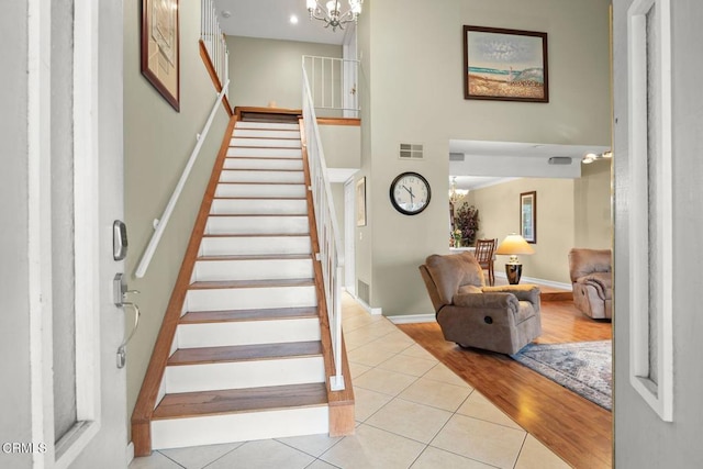 stairs featuring tile patterned flooring, visible vents, baseboards, and a notable chandelier