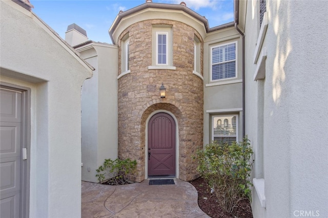 doorway to property featuring stone siding and stucco siding