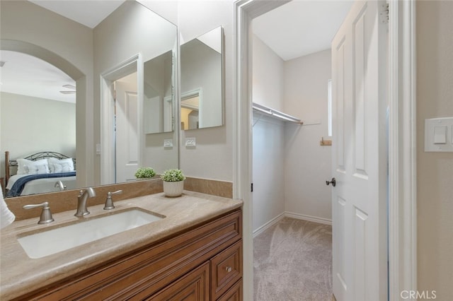 bathroom featuring a walk in closet, ensuite bathroom, and vanity