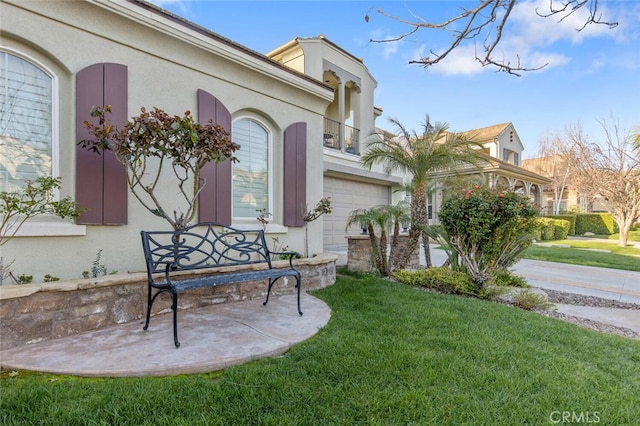 view of exterior entry with a yard, an attached garage, and stucco siding
