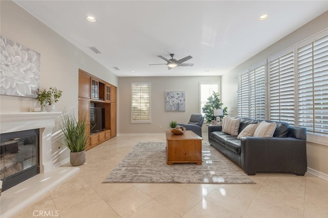 living area with baseboards, ceiling fan, a fireplace, and recessed lighting
