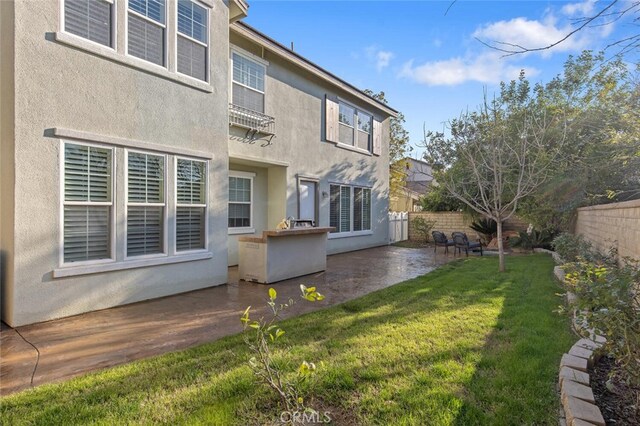 back of property with a yard, a patio, a fenced backyard, and stucco siding