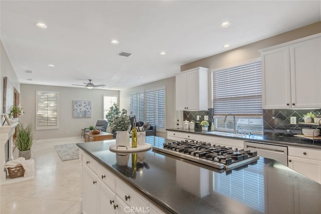 kitchen with visible vents, dark countertops, a sink, dishwasher, and stainless steel gas stovetop
