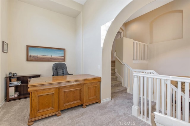 office with baseboards, arched walkways, and light carpet
