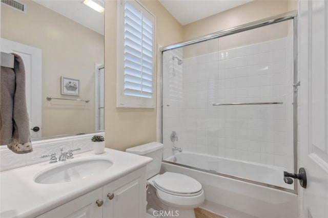 full bath featuring vanity, combined bath / shower with glass door, toilet, and visible vents