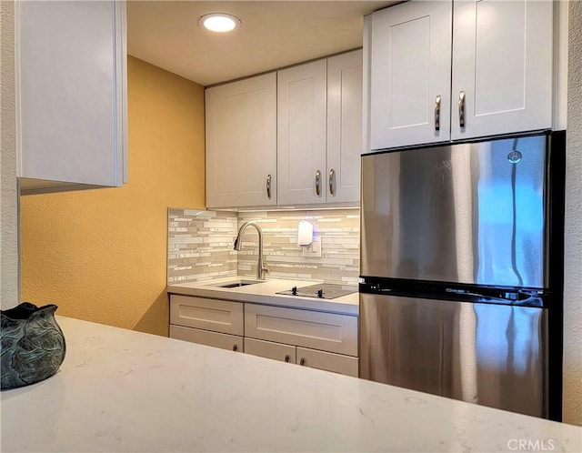 24055 Paseo Del Lago W Unit 1455, Laguna Woods, CA 92637 - kitchen featuring black electric cooktop, white cabinetry, a sink, backsplash, and freestanding refrigerator