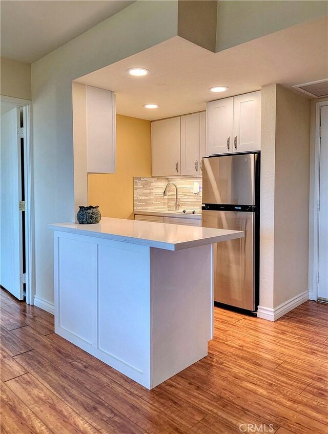 24055 Paseo Del Lago W Unit 1455, Laguna Woods, CA 92637 - kitchen featuring white cabinets, backsplash, light wood-type flooring, and freestanding refrigerator