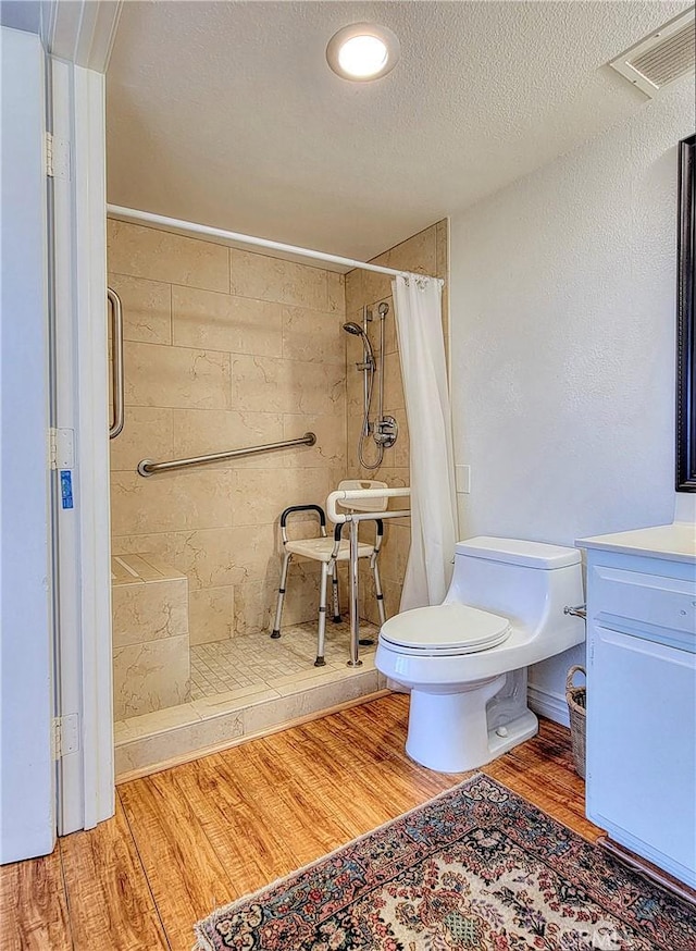 24055 Paseo Del Lago W Unit 1455, Laguna Woods, CA 92637 - bathroom with a tile shower, toilet, a textured ceiling, visible vents, and wood finished floors