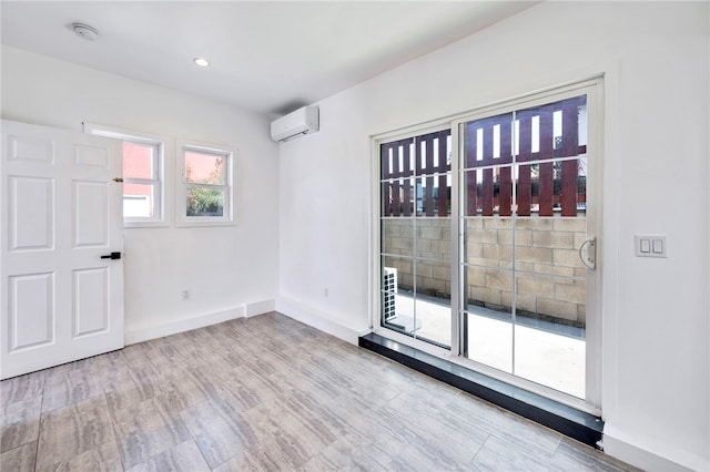 spare room featuring an AC wall unit, baseboards, and wood finished floors