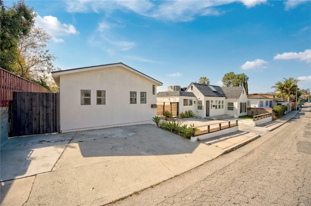 view of front facade with stucco siding, roof mounted solar panels, fence, and a residential view