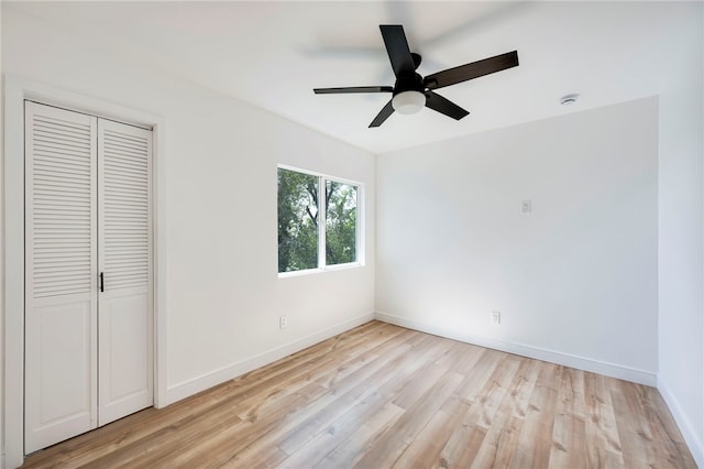 unfurnished bedroom featuring baseboards, a ceiling fan, light wood-style floors, and a closet
