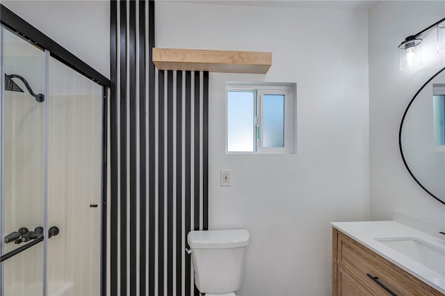 bathroom featuring toilet, vanity, and a shower