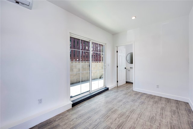 unfurnished room with a wealth of natural light, wood finished floors, and a wall mounted AC