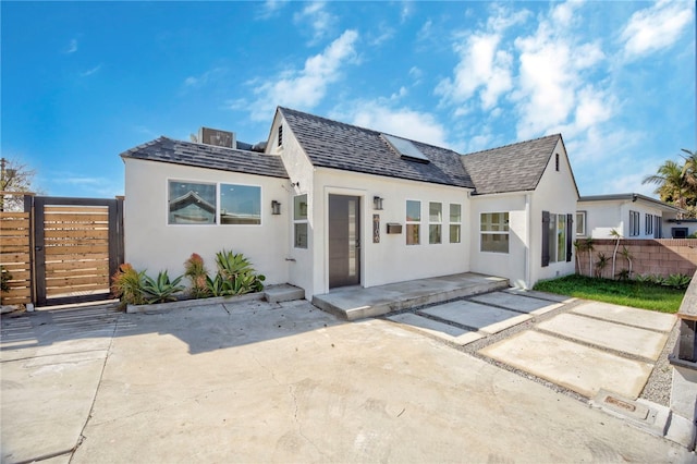 rear view of property featuring a patio area, stucco siding, and fence