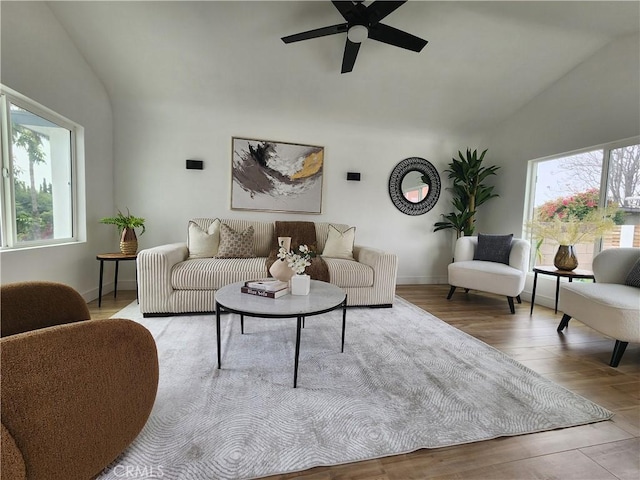 living area with baseboards, wood finished floors, high vaulted ceiling, and ceiling fan