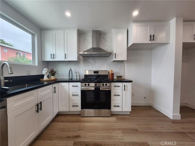 kitchen with wall chimney range hood, stainless steel range with gas cooktop, decorative backsplash, and a sink