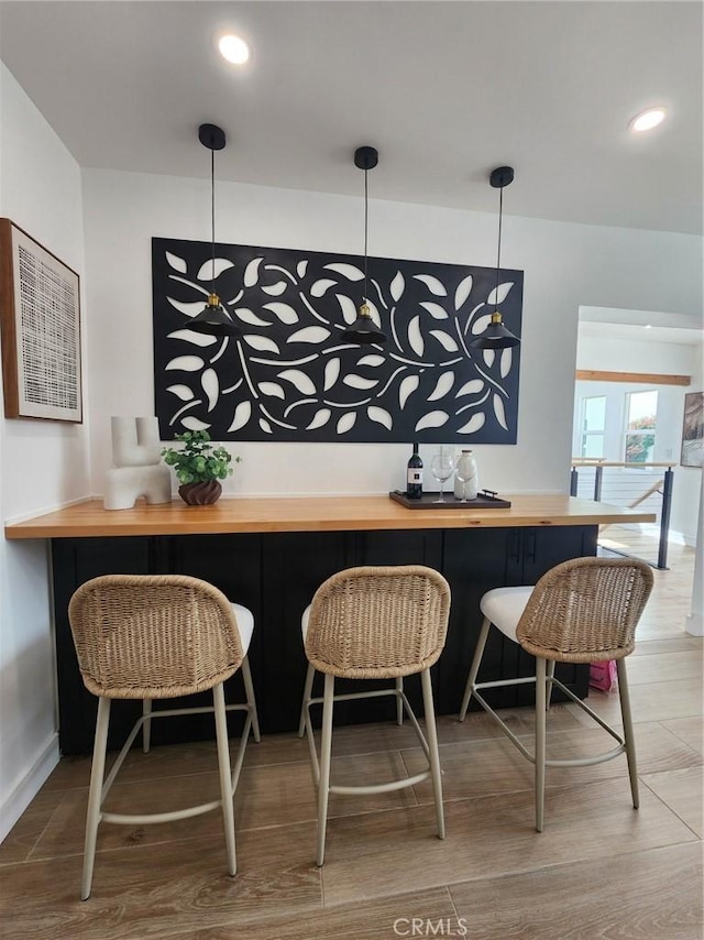 bar with pendant lighting and wood finished floors