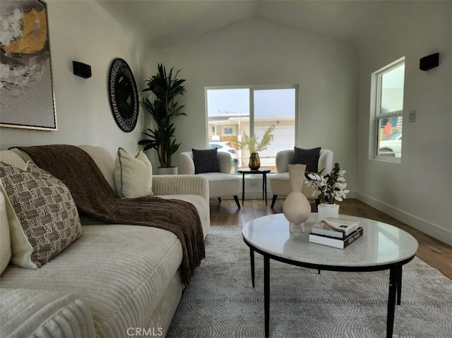 living area with vaulted ceiling, wood finished floors, and baseboards