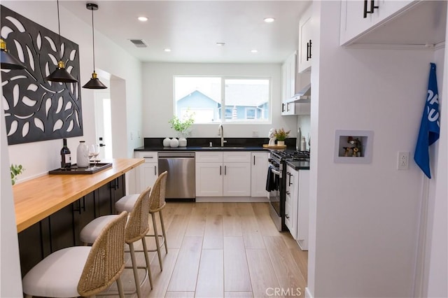 5106 O Sullivan Dr, Los Angeles, CA 90032 - kitchen with appliances with stainless steel finishes, a sink, white cabinets, pendant lighting, and a breakfast bar area
