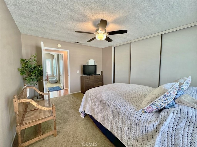 carpeted bedroom featuring a textured ceiling, ceiling fan, and a closet
