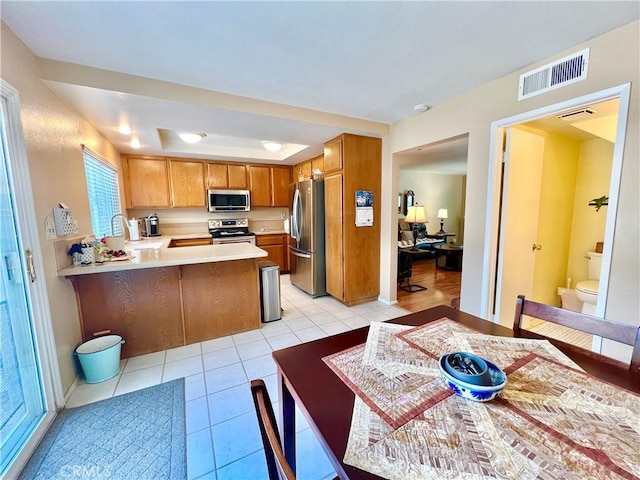 kitchen with visible vents, light countertops, light tile patterned floors, a peninsula, and stainless steel appliances