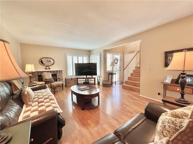 living room featuring a fireplace, stairs, and wood finished floors