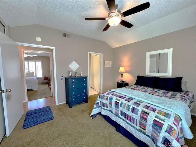 bedroom with ceiling fan, light carpet, vaulted ceiling, and visible vents