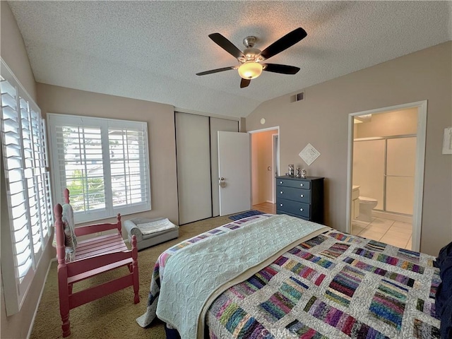 bedroom with a closet, visible vents, ensuite bathroom, a textured ceiling, and vaulted ceiling