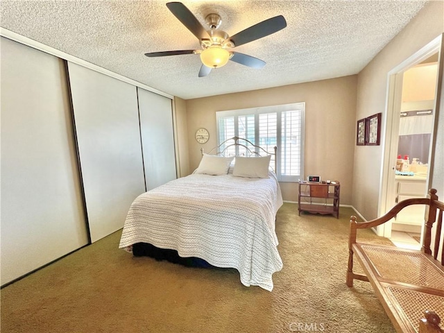 carpeted bedroom featuring a closet, a ceiling fan, a textured ceiling, and connected bathroom