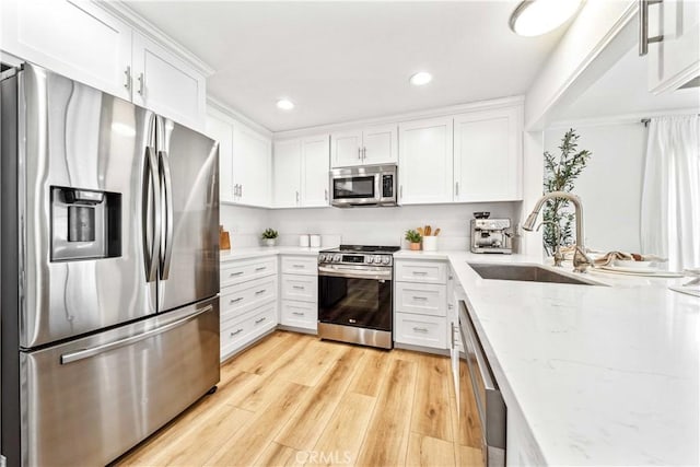 22287 Modina, Laguna Hills, CA 92653 - kitchen with appliances with stainless steel finishes, a sink, white cabinets, light stone counters, and light wood-style floors
