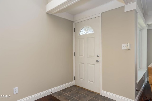 foyer entrance with baseboards and dark tile patterned flooring