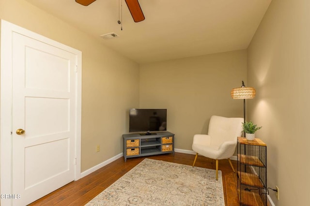 living area with visible vents, baseboards, a ceiling fan, and dark wood-style flooring