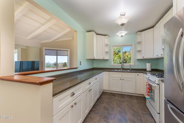 kitchen with dark countertops, a sink, white appliances, white cabinetry, and open shelves