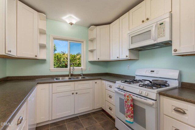 kitchen with dark countertops, open shelves, white appliances, white cabinetry, and a sink