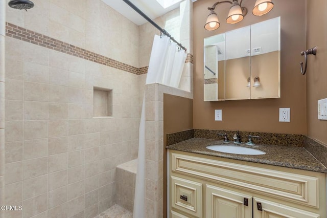 full bath featuring a skylight, visible vents, tiled shower, and vanity