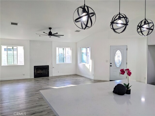 foyer entrance featuring visible vents, wood finished floors, a large fireplace, baseboards, and ceiling fan