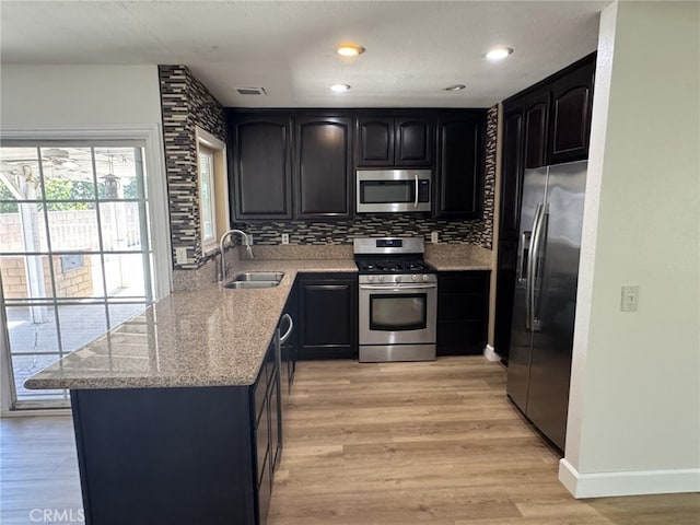 7524 Matterhorn Ave, Rancho Cucamonga, CA 91730 - kitchen with stainless steel appliances, light stone countertops, light wood-type flooring, tasteful backsplash, and dark cabinetry