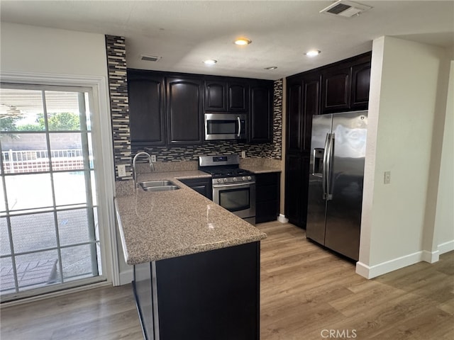 7524 Matterhorn Ave, Rancho Cucamonga, CA 91730 - kitchen featuring appliances with stainless steel finishes, backsplash, light stone countertops, light wood-style flooring, and a peninsula