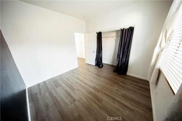 spare room with baseboards and wood finished floors