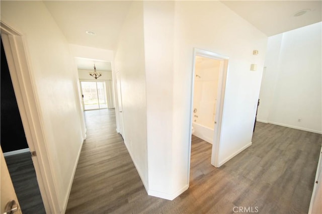 hallway with an inviting chandelier, wood finished floors, and baseboards