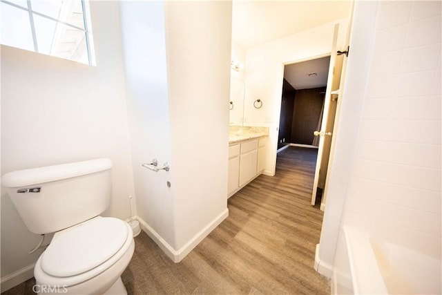 bathroom with toilet, wood finished floors, and baseboards