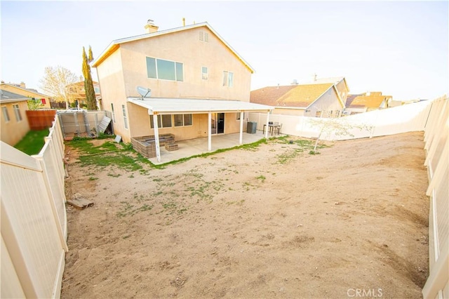 back of house featuring stucco siding, a patio area, a fenced backyard, and a chimney