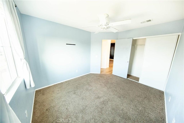 unfurnished bedroom featuring visible vents, a ceiling fan, a closet, and carpet flooring