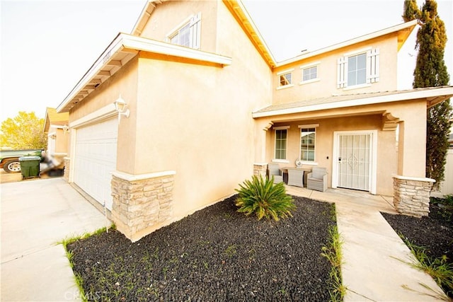 view of front of property featuring stucco siding, stone siding, an attached garage, and driveway