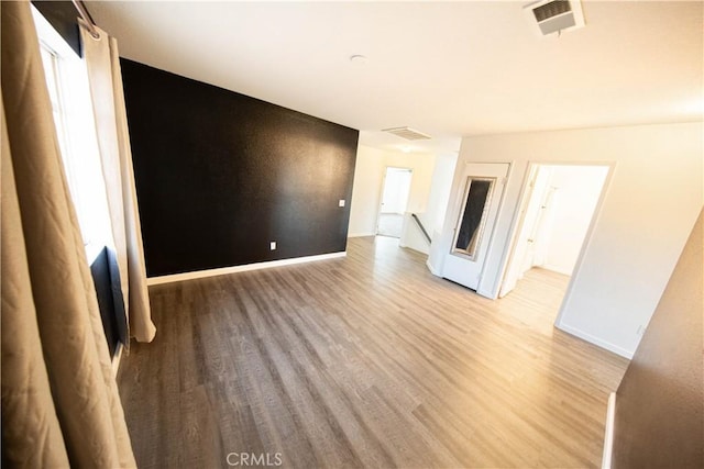 unfurnished living room featuring visible vents, light wood-type flooring, and baseboards