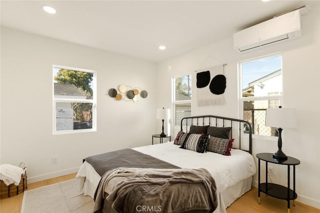 bedroom with recessed lighting, multiple windows, light wood-style flooring, and a wall unit AC