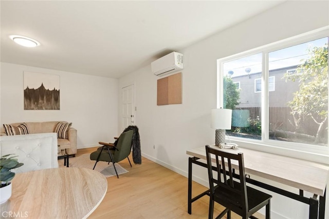 interior space featuring baseboards, light wood-style flooring, and a wall unit AC