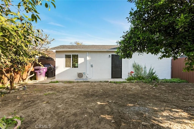 rear view of house featuring ac unit, stucco siding, and fence